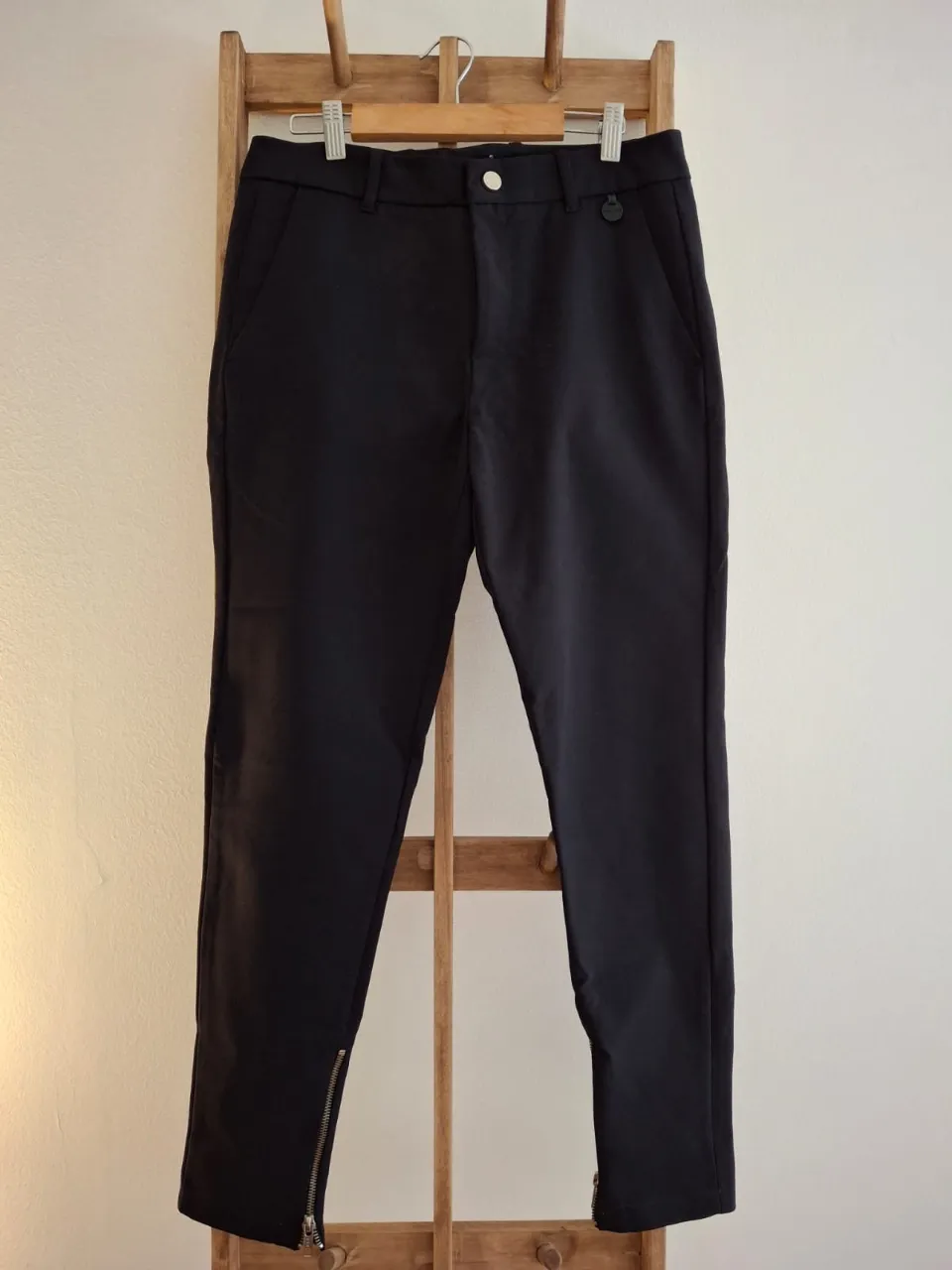 Pantalón sastrero negro de mujer, con cierre en el tobillo. Ideal para un look elegante y moderno.