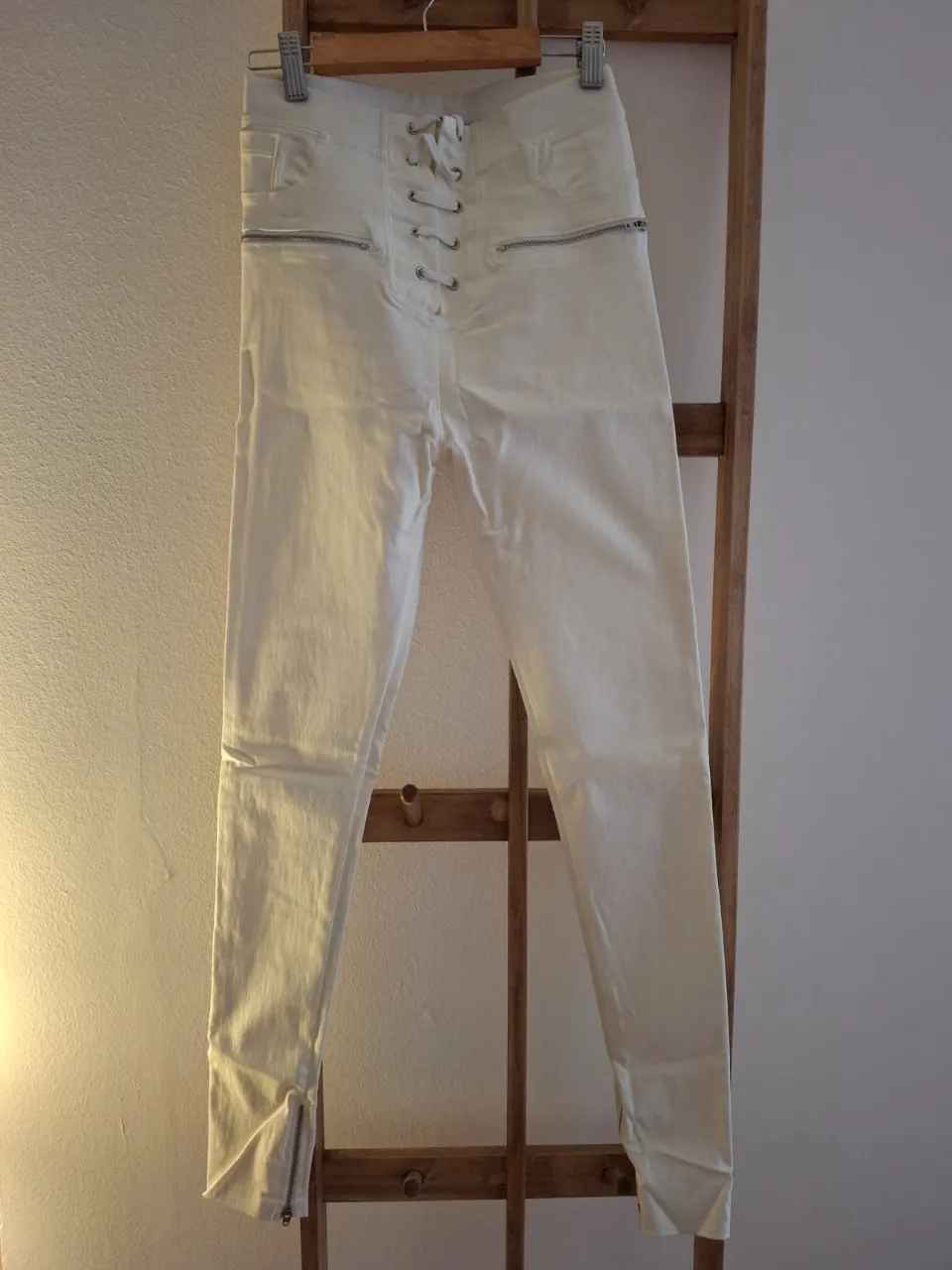 Pantalón blanco de mujer con detalle de ajuste frontal con cordones y cierre en los tobillos. Ideal para un look moderno y sofisticado.