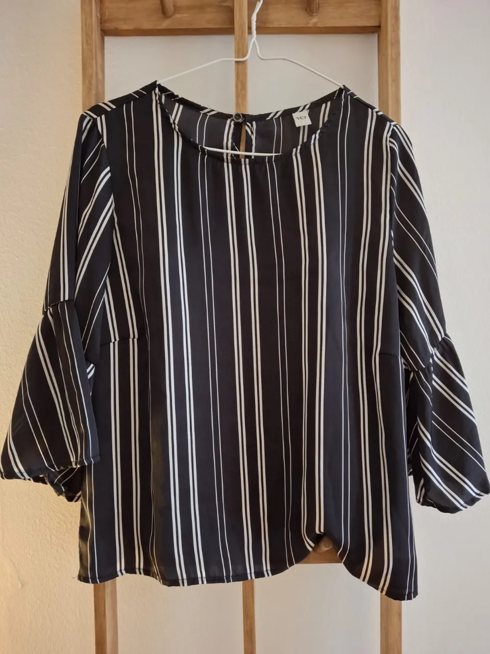 Blusa de mujer a rayas verticales en blanco y negro, con mangas 3/4 acampanadas. Ideal para un look elegante y moderno.