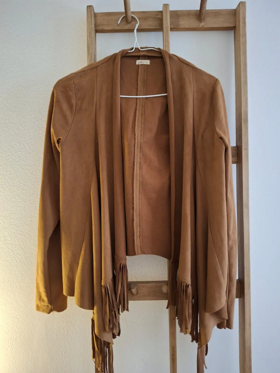 Abrigo de gamuza marrón con flecos en el bajo. Ideal para un look boho y casual.
