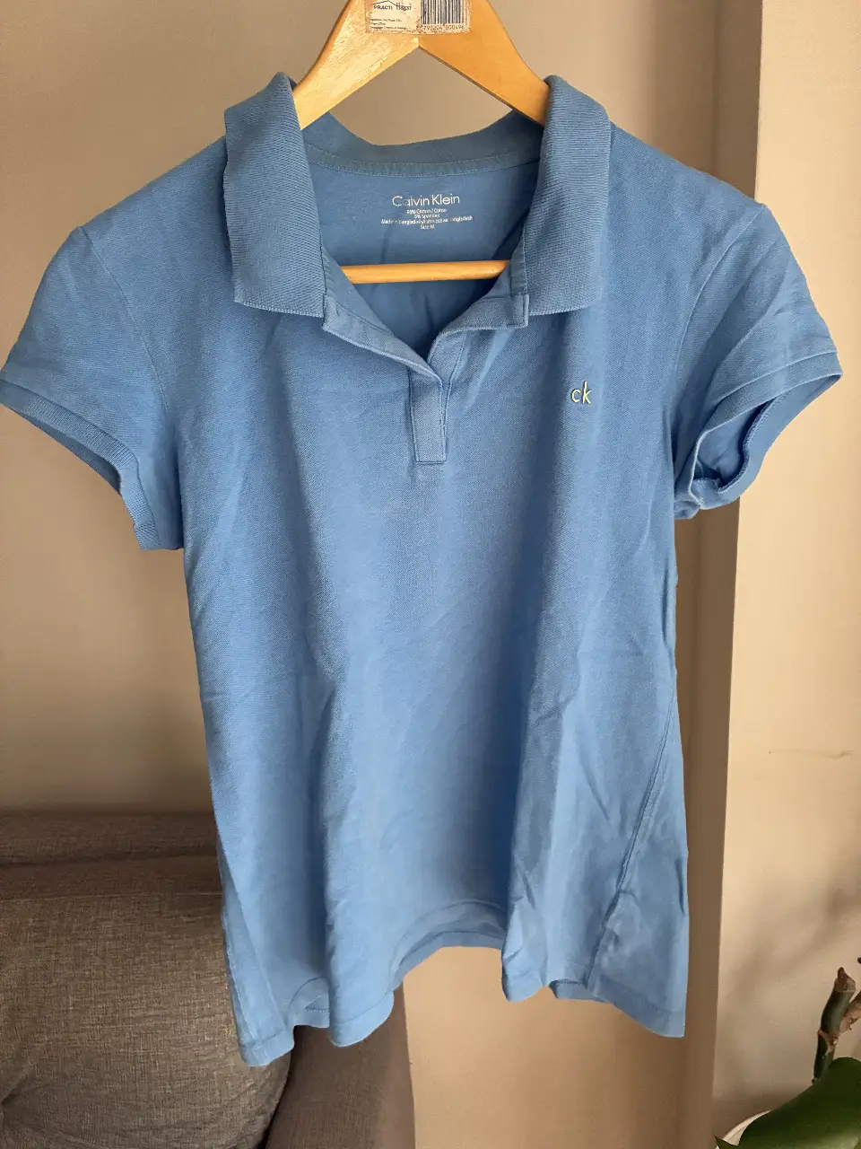 Remera polo celeste de mujer Calvin Klein. Confeccionada en algodón y spandex, ideal para un look casual.