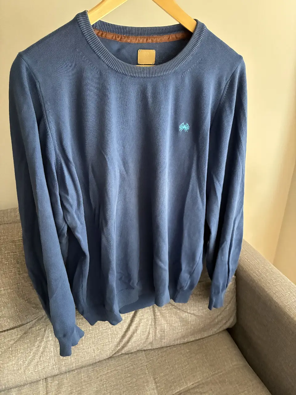 Sweater azul de hombre con coderas marrones. Cuello redondo y detalle de etiqueta en el cuello. Ideal para un look casual y abrigado.
