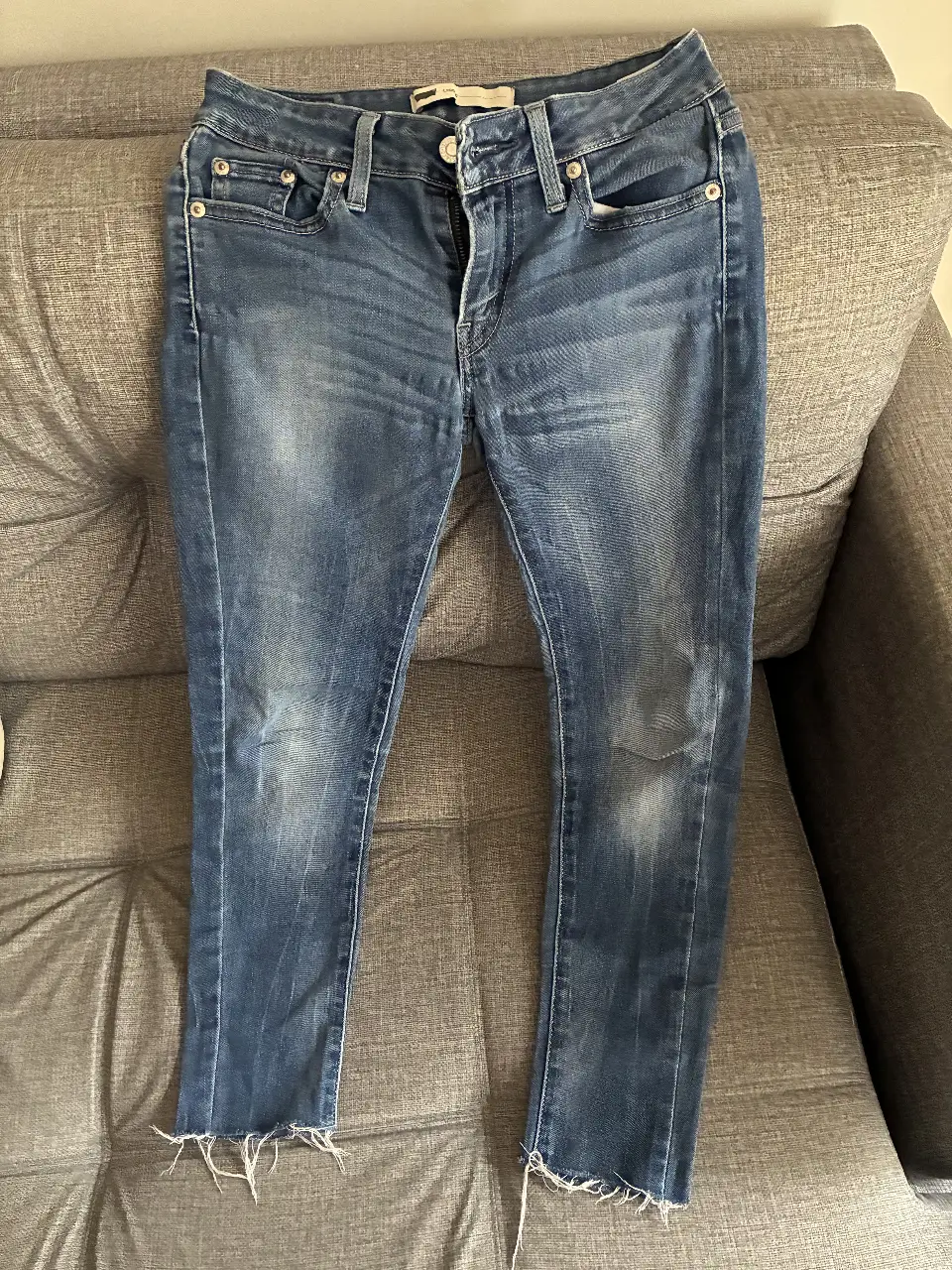 Jeans de mujer, azul, con corte por los tobillos y detalles de desgaste. Marca Levi's.