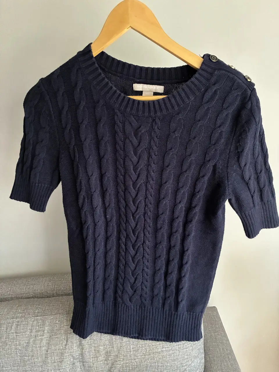 Sweater de mujer azul marino con diseño de trenzas y botones en los hombros. Ideal para un look preppy y elegante.