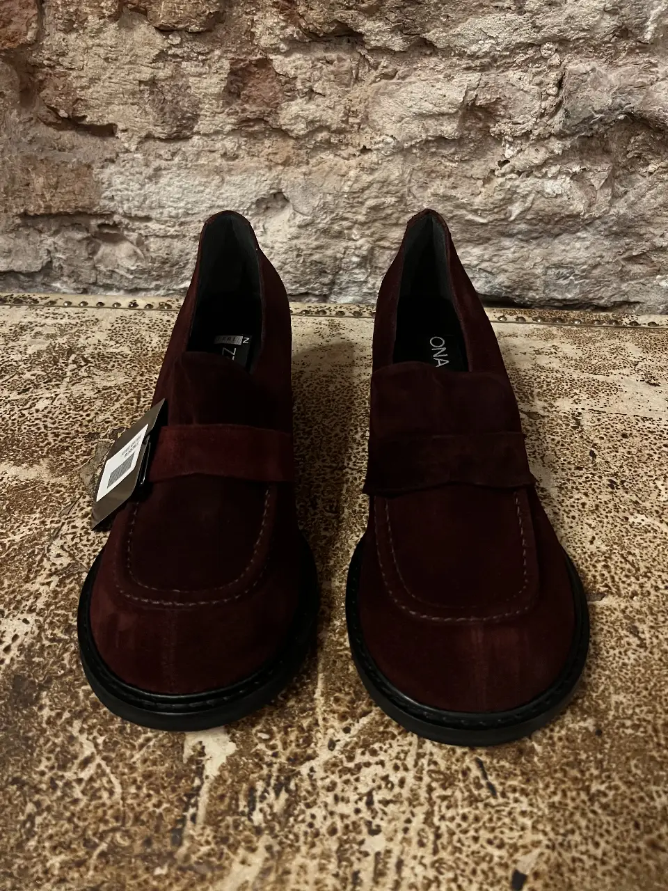 Botines de gamuza color borgoña con taco cuadrado y suela de goma. Diseño de mocasín con solapa en el empeine. Ideales para un look elegante y cómodo. bordó oscuro casi marrón.