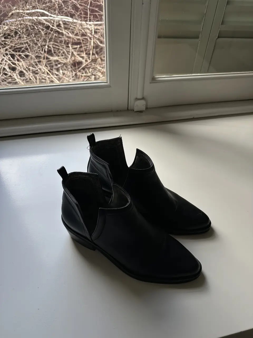 Botines negros de cuero con diseño moderno y corte en el empeine. Ideales para un look sofisticado y versátil.