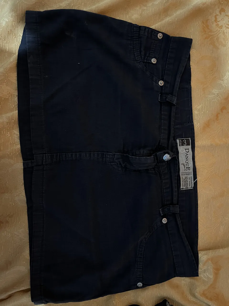 Pollera de jean negra, tiro bajo, con detalles de bolsillos y botones. Ideal para un look casual y moderno.