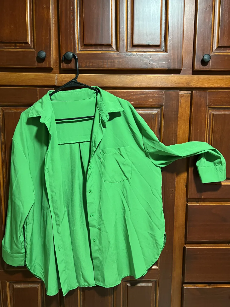 Camisa verde con mangas largas y botones al frente. Posee un bolsillo en el lado izquierdo.