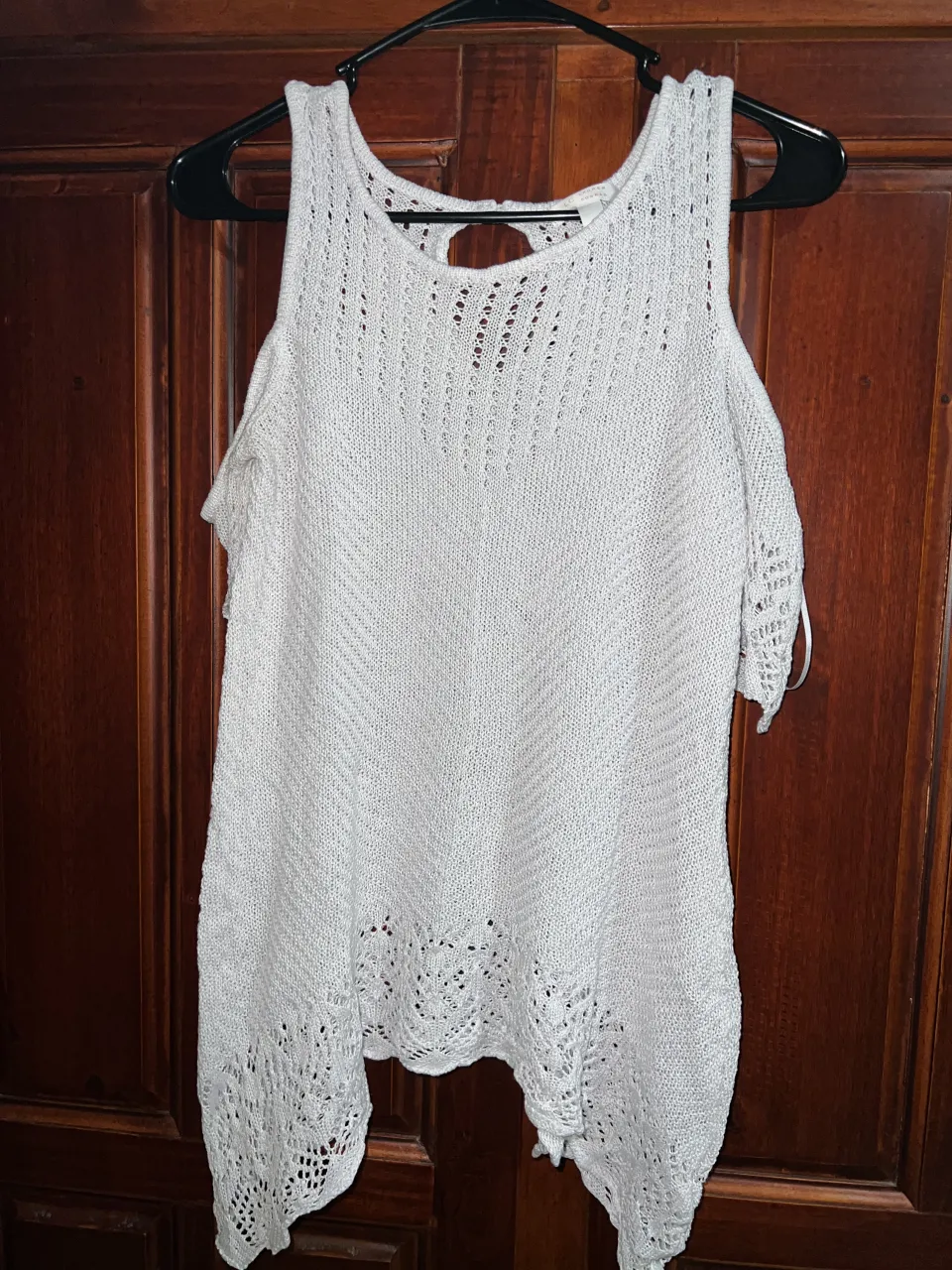 Remera blanca de tejido abierto con mangas cortas y hombros descubiertos. Posee un detalle de recorte en la espalda.