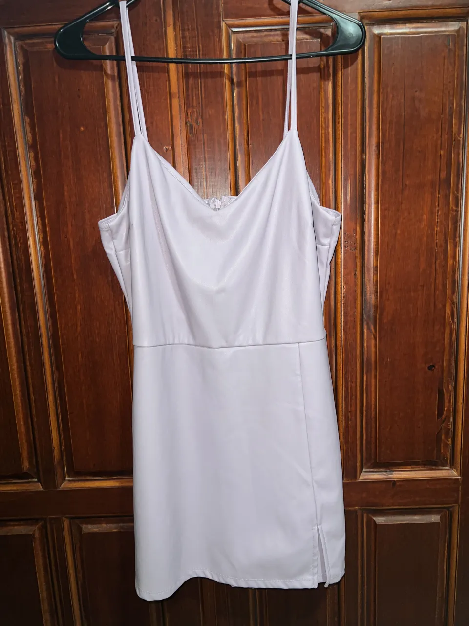 Vestido lila pastel con tiras finas y escote en V. Posee un corte a la cintura y una pequeña abertura lateral en la falda/short. Es pollera pantalón.