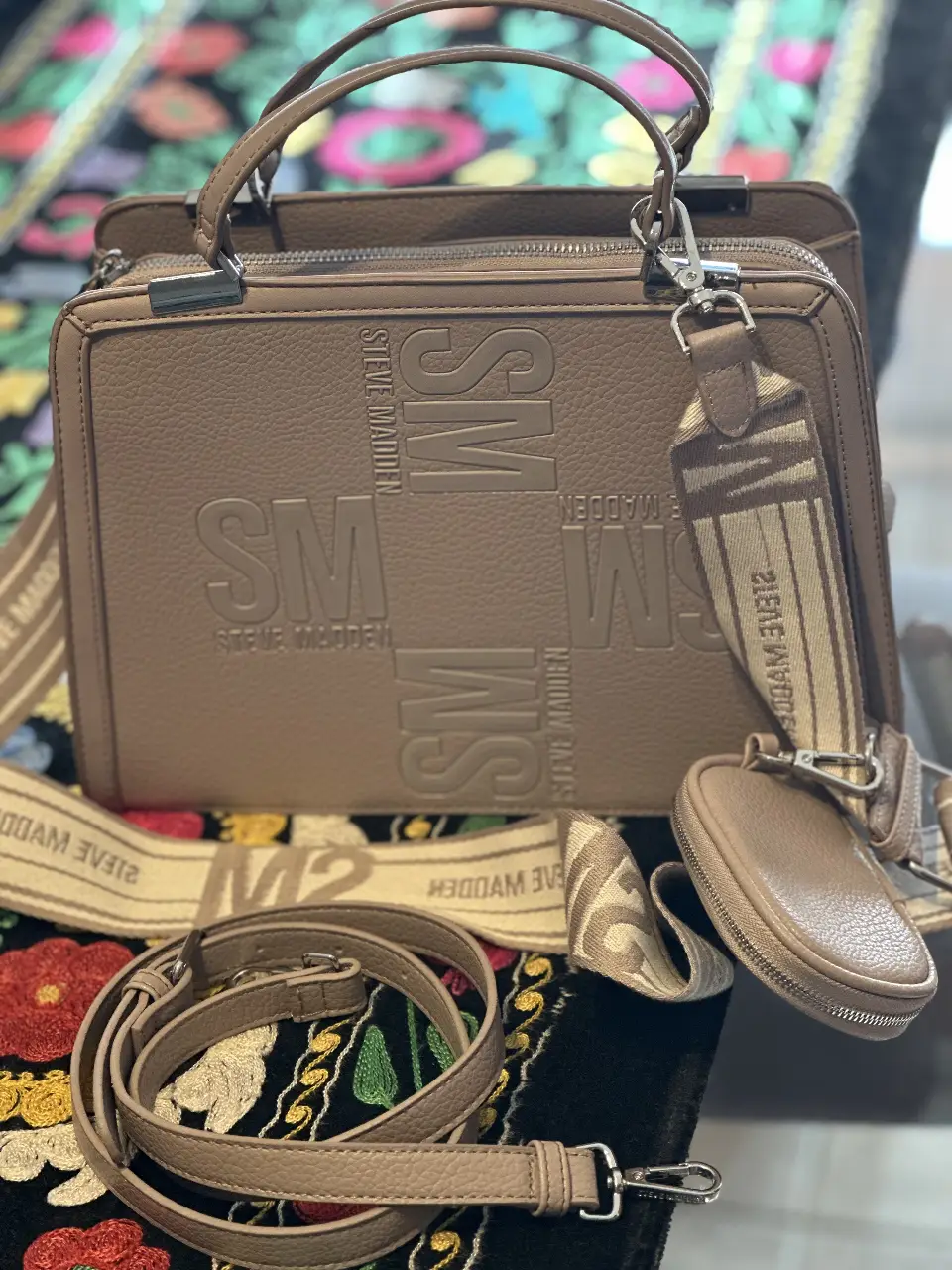 Cartera Steve Madden color marrón, con correa ajustable y detalles de la marca en relieve. Incluye un monedero a juego y una correa adicional.
