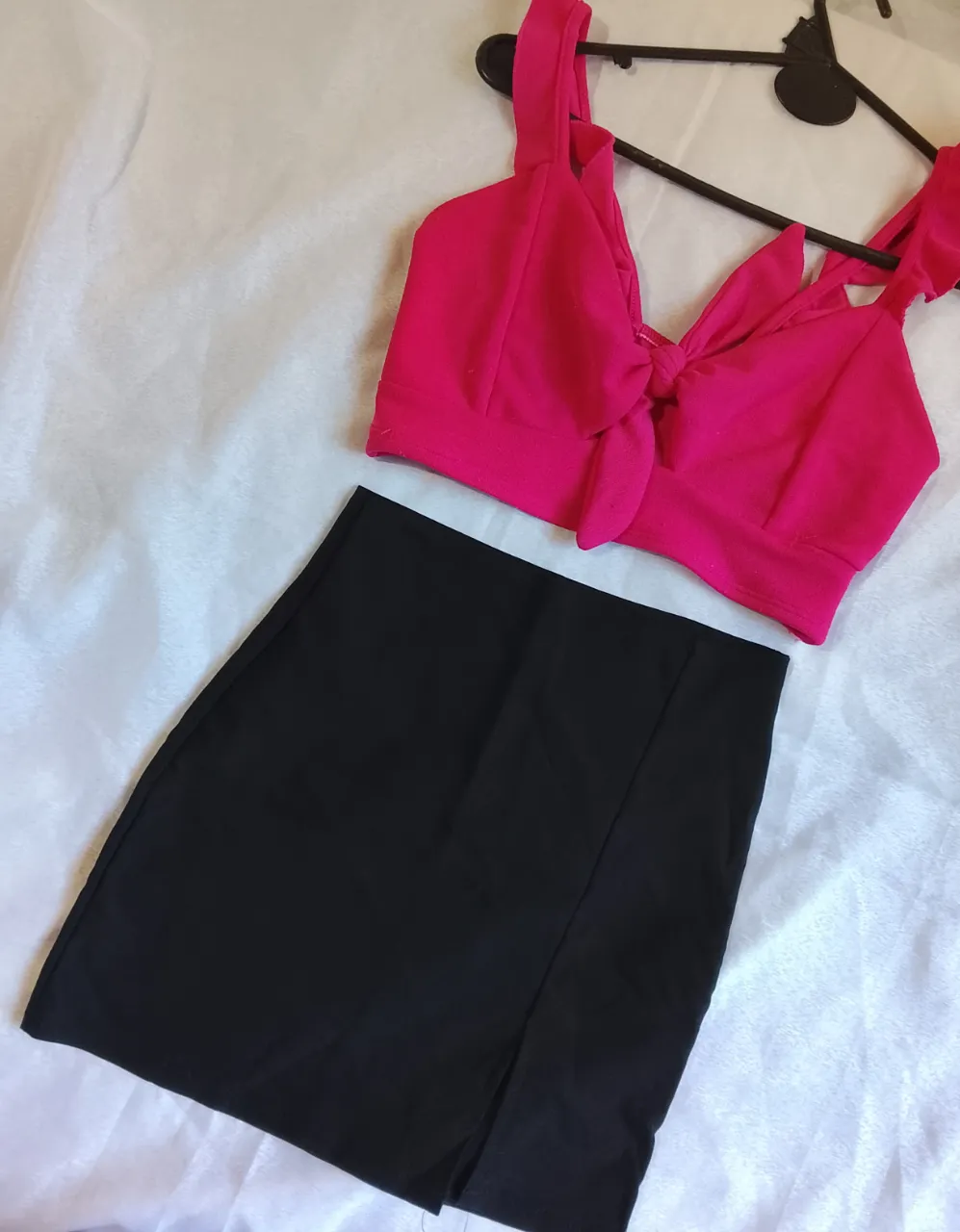 Conjunto de top fucsia con nudo en el frente y falda negra con tajos laterales.