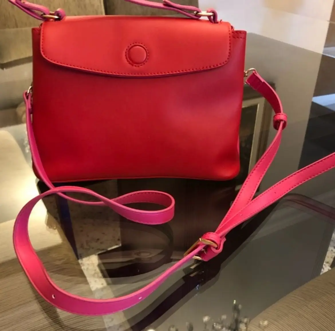Cartera roja con manijas y correa rosa. Diseño moderno y elegante, ideal para cualquier ocasión. Correa desmontable. 