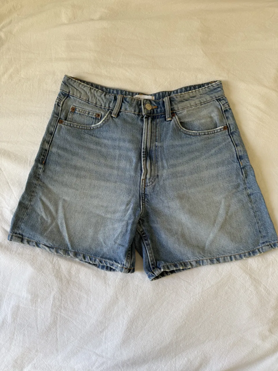 Shorts de jean tiro alto, color azul claro. Posee bolsillos delanteros y traseros.