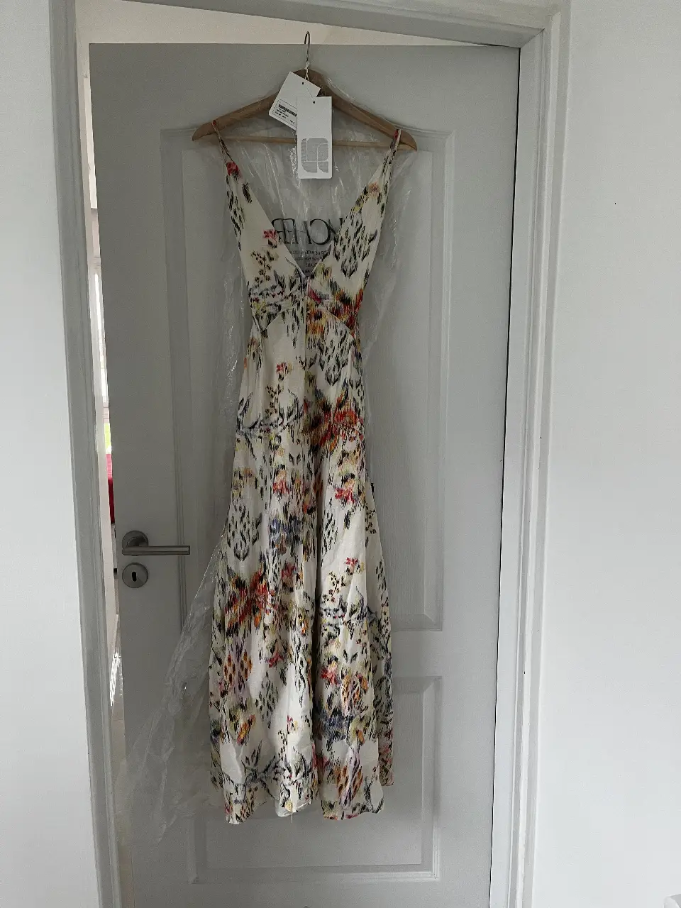 Vestido largo de mujer con estampado floral en tonos blanco, amarillo, naranja y azul. Diseño con tirantes finos y espalda descubierta. Ideal para eventos especiales o salidas de verano.