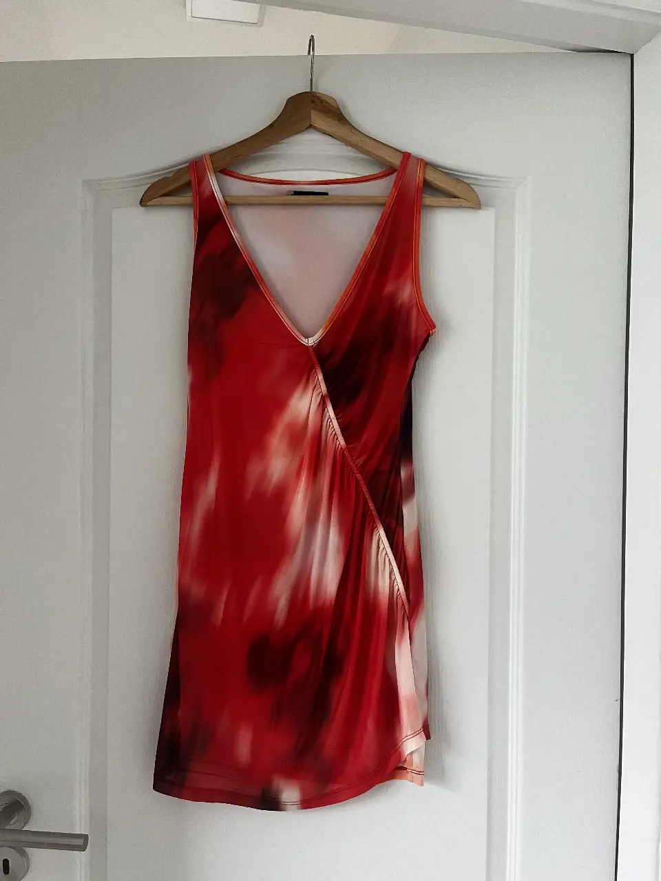 Vestido mini de mujer, con diseño abstracto en tonos rojos y naranjas. Escote en V y detalle drapeado. Marca Tucci, talle XS.