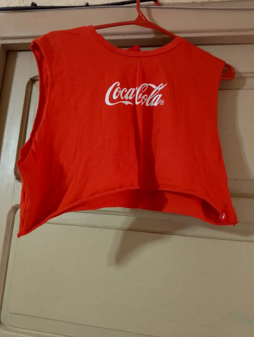 Top crop rojo con estampado de Coca-Cola en blanco. Ideal para un look casual y moderno.