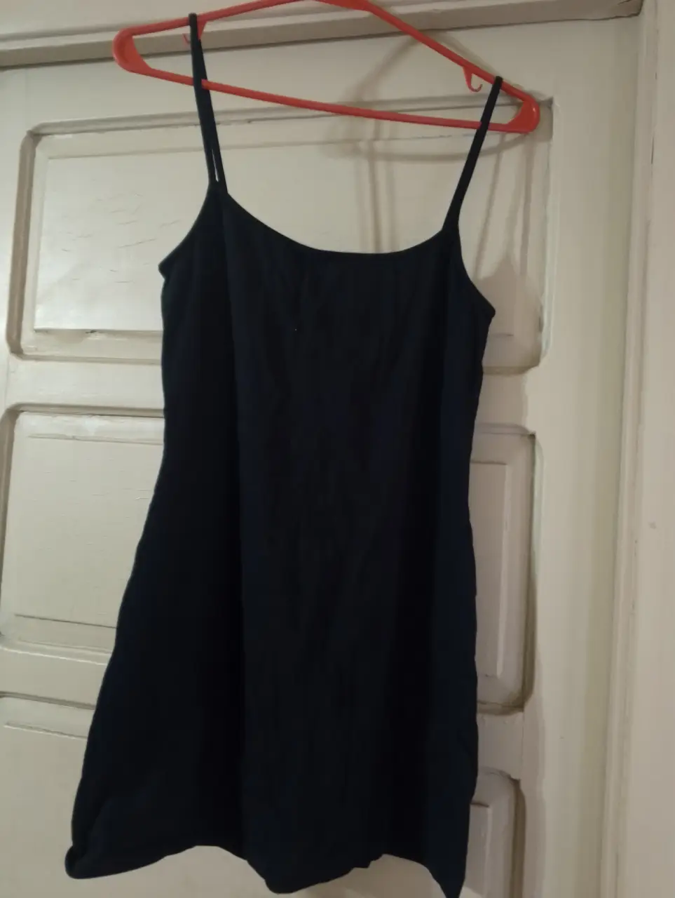 Vestido negro corto con tirantes finos, ideal para una salida casual o una fiesta. Diseño simple y elegante.