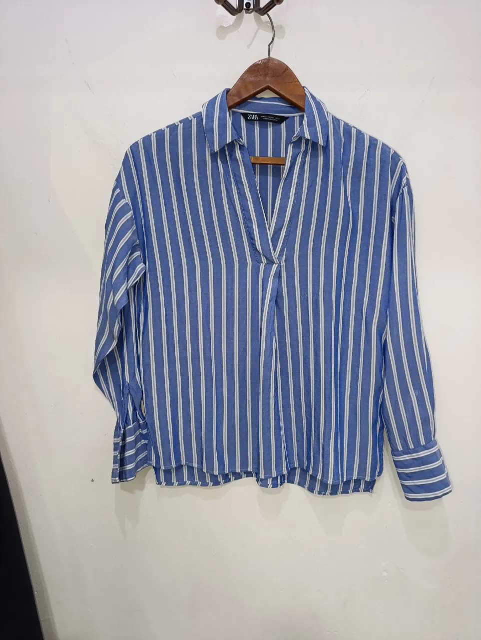 Camisa de mangas largas a rayas verticales azules y blancas. Posee cuello y botones al frente.