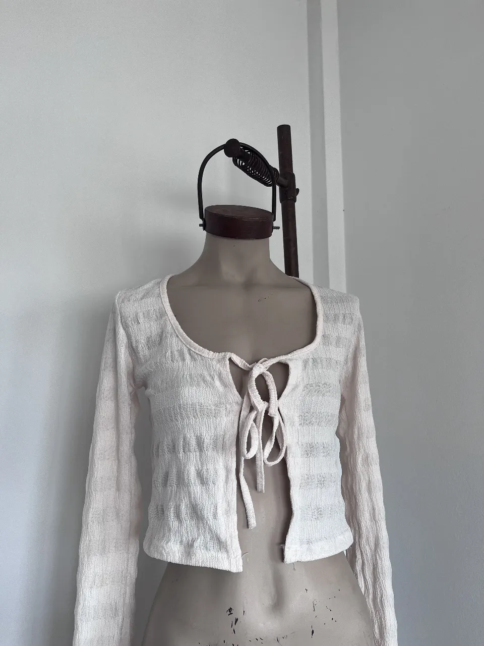 Cardigan tejido blanco con tiritas para atar en el escote. Manga larga y textura sutil.