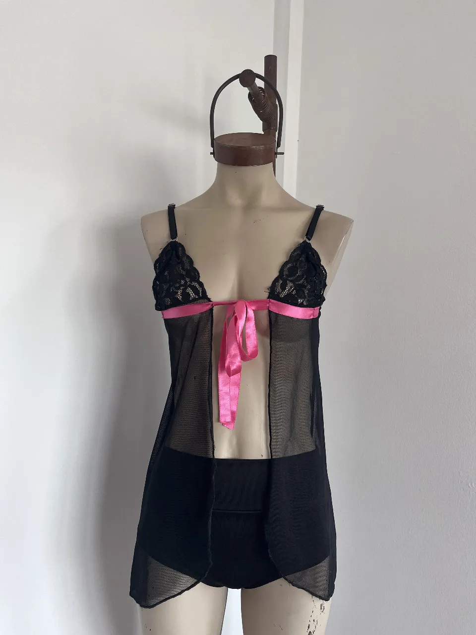 Camisolín de lencería negro con detalles en encaje y cinta de raso rosa. Tiene un corpiño con tiras regulables. no incluye el short tiro alto.
