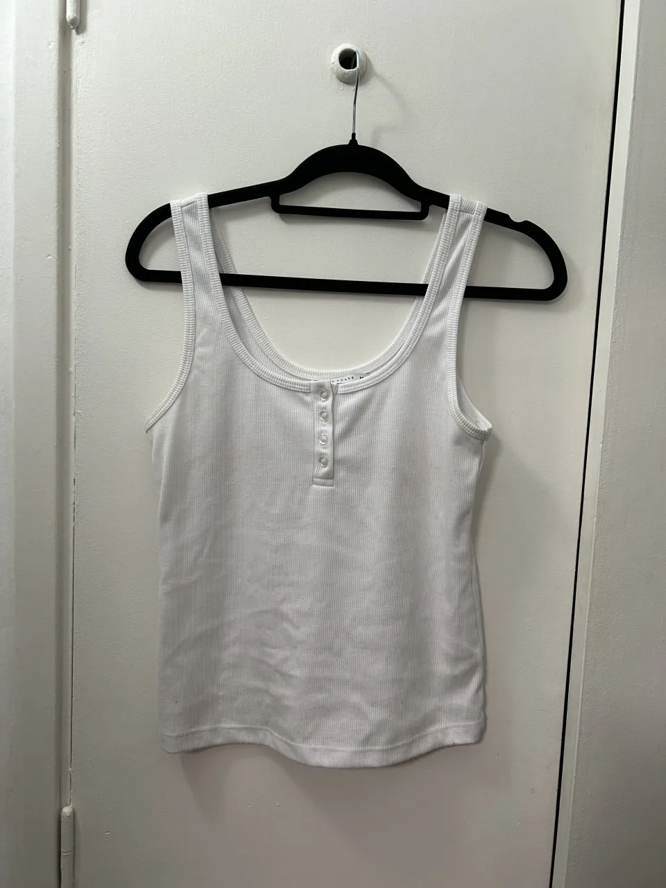 Musculosa blanca acanalada con botones en la parte delantera.
