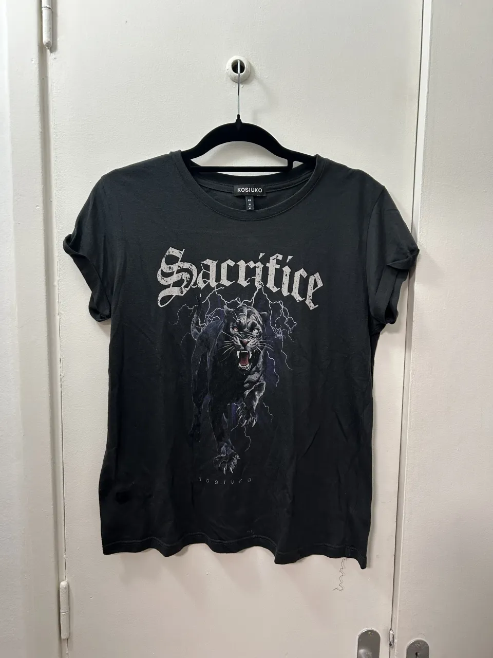 Remera negra con estampa de pantera y el texto "Sacrifice" en la parte delantera.