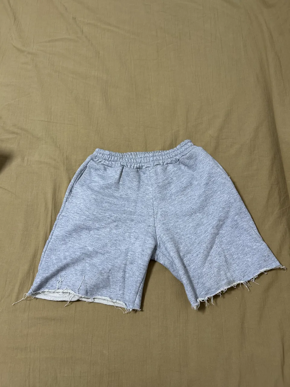 Shorts grises de algodón con cintura elastizada y borde inferior deshilachado.
