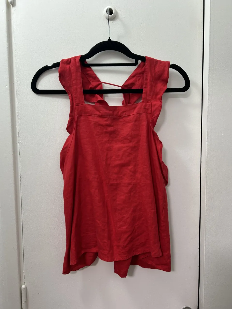 Remera roja con tiras finas y detalle de volados en los hombros. Espalda con tiras cruzadas.