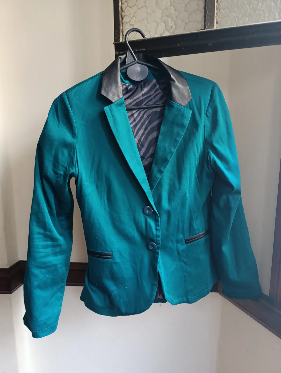 Blazer de mujer en color verde esmeralda con solapas negras. Diseño elegante con un botón y forro interior con estampado de cebra. Ideal para un look sofisticado.