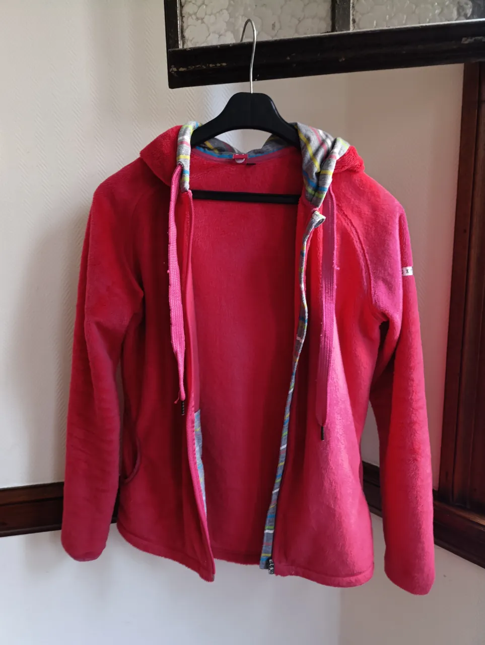 Buzo con cierre y capucha para mujer, de color rojo. Tiene un forro interior con diseño multicolor en la capucha y en los bordes de la cremallera y bolsillos. La marca es Roxy y el talle es S.
