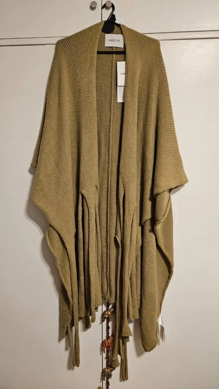 Poncho tejido de lana en color crudo, con flecos largos y detalles de diseño únicos. Ideal para un look comfy y elegante.