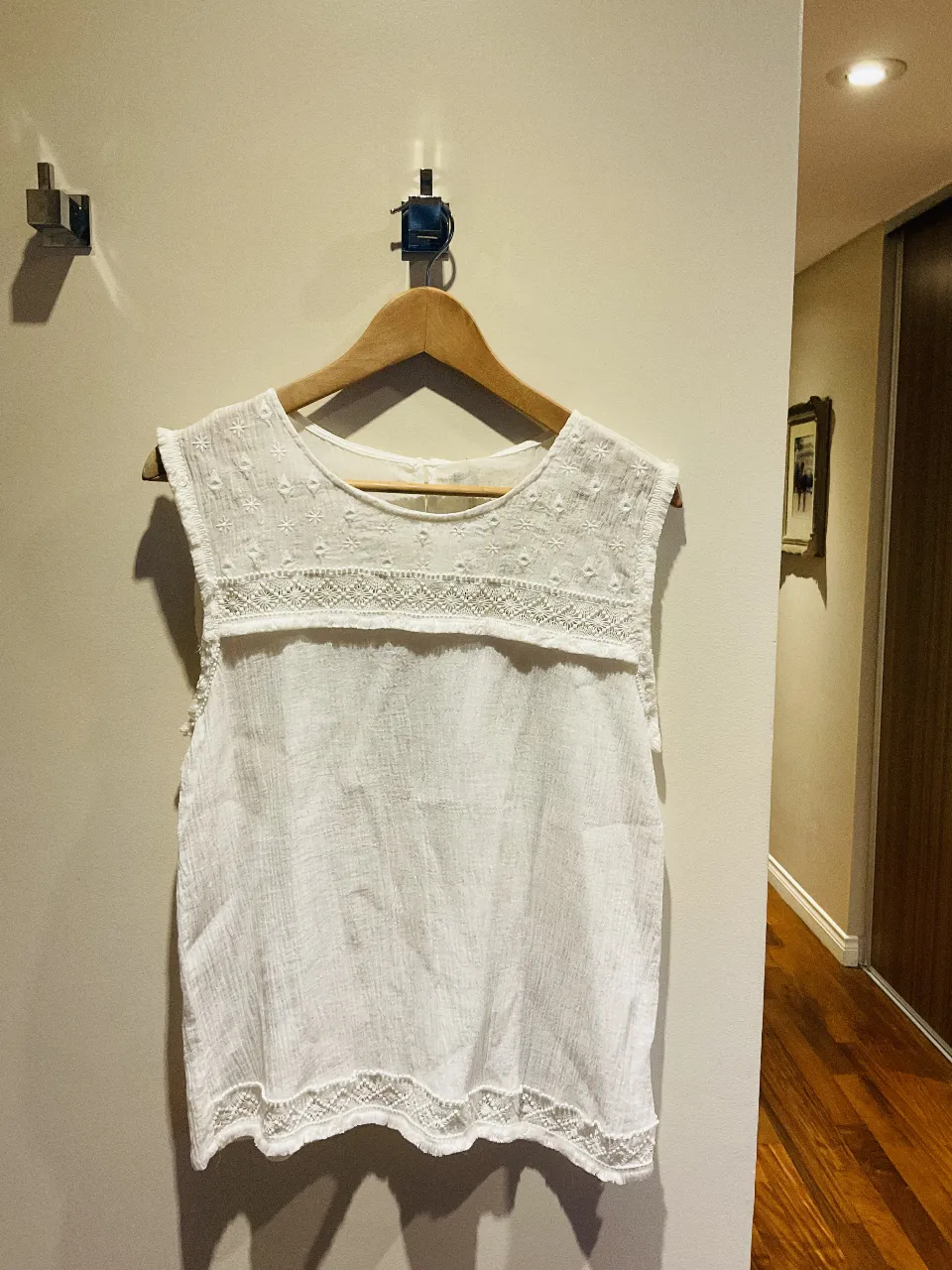 Musculosa blanca de algodón con detalles de bordado y puntilla en el cuello y ruedo. Ideal para un look fresco y bohemio.