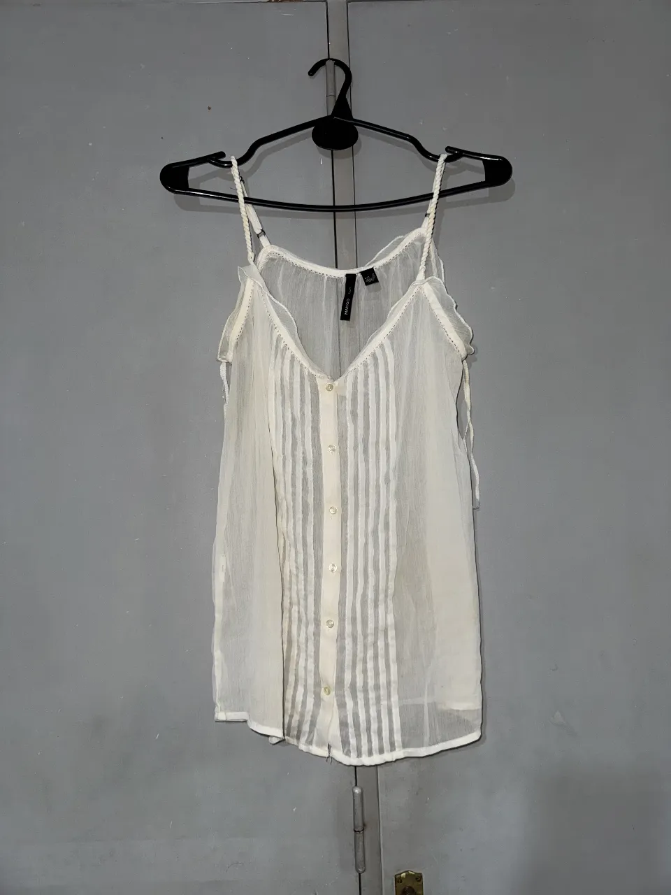 Blusa de mujer, color blanco, con tirantes finos y botones delanteros. Diseño delicado y fresco, ideal para el verano.
