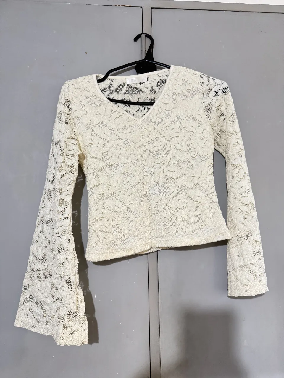 Blusa de encaje blanca con mangas largas acampanadas, ideal para un look romántico y elegante. Perfecta para una salida o evento especial.