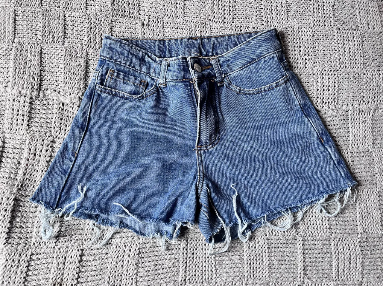 Shorts de jean tiro alto con roturas y detalles deshilachados en los bordes. Un clásico infaltable para looks casuales y cancheros. Ideales para combinar con tops, remeras o camisas.