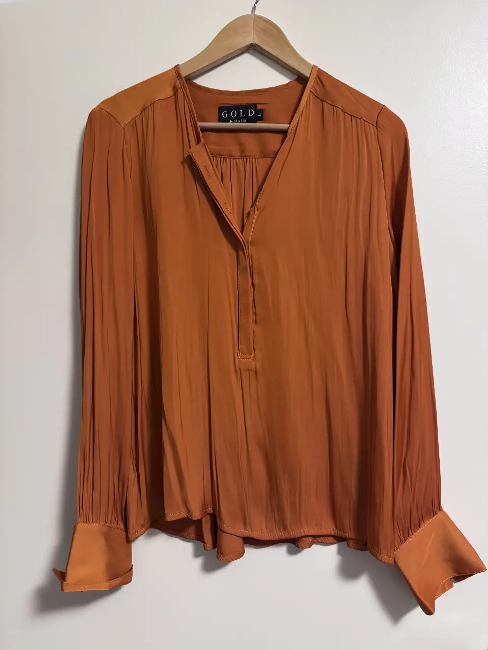 Blusa naranja de seda con mangas largas y puños anchos. Cuello en V y detalle de botones.