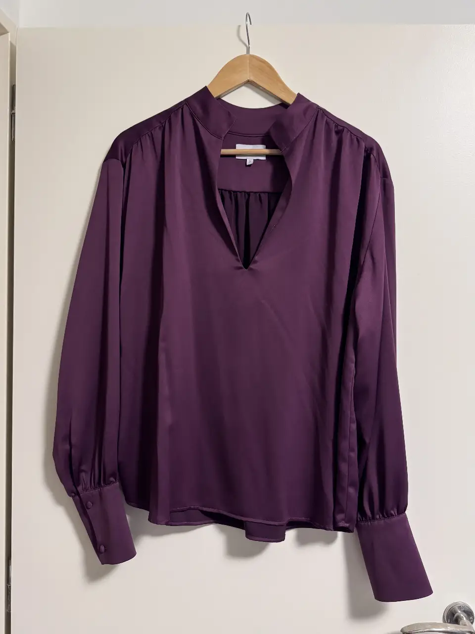 Blusa de satén morada con cuello en V y mangas largas con puños abotonados. Ideal para un look elegante y sofisticado.
