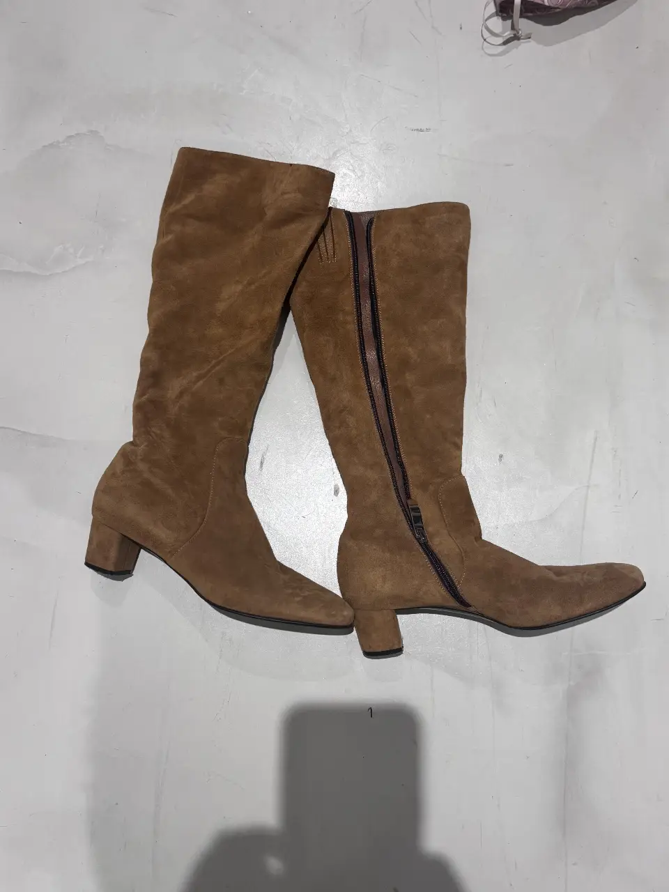 Botas de caña alta de gamuza marrón, con cierre lateral y taco cuadrado. Ideales para un look elegante y abrigado.