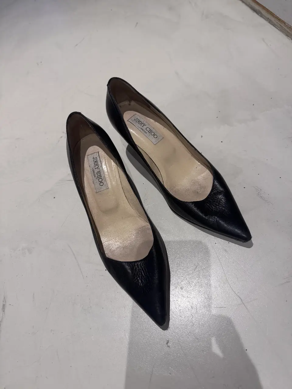 Elegantes zapatos de tacón Jimmy Choo negros, ideales para eventos formales o salidas nocturnas. Confeccionados en cuero de alta calidad, estos zapatos usados ofrecen un toque de sofisticación y estilo atemporal.
