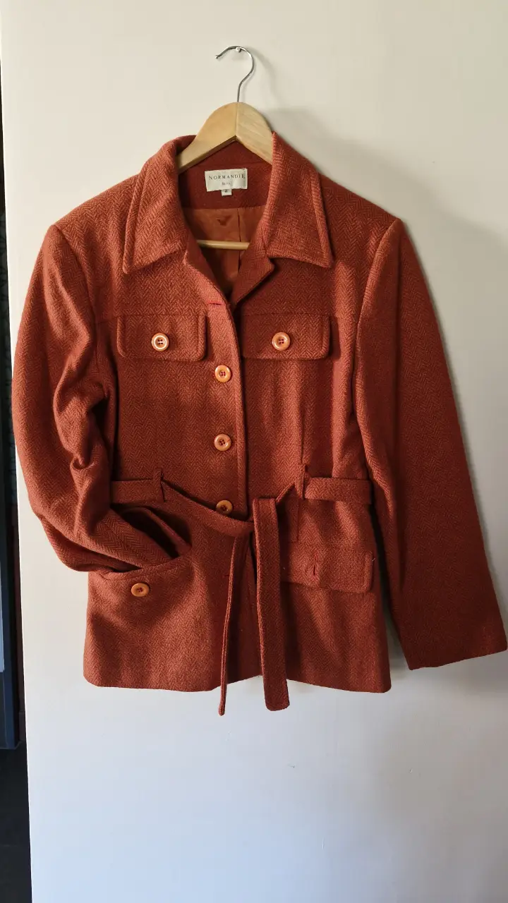 Chaqueta vintage color marrón con cinturón. Posee bolsillos delanteros y botones. Ideal para un look retro.