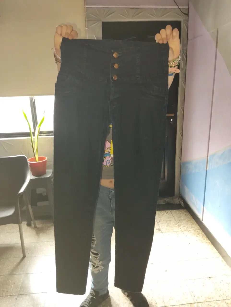 Jeans negro tiro alto con botones dorados. Ideal para un look casual y moderno.