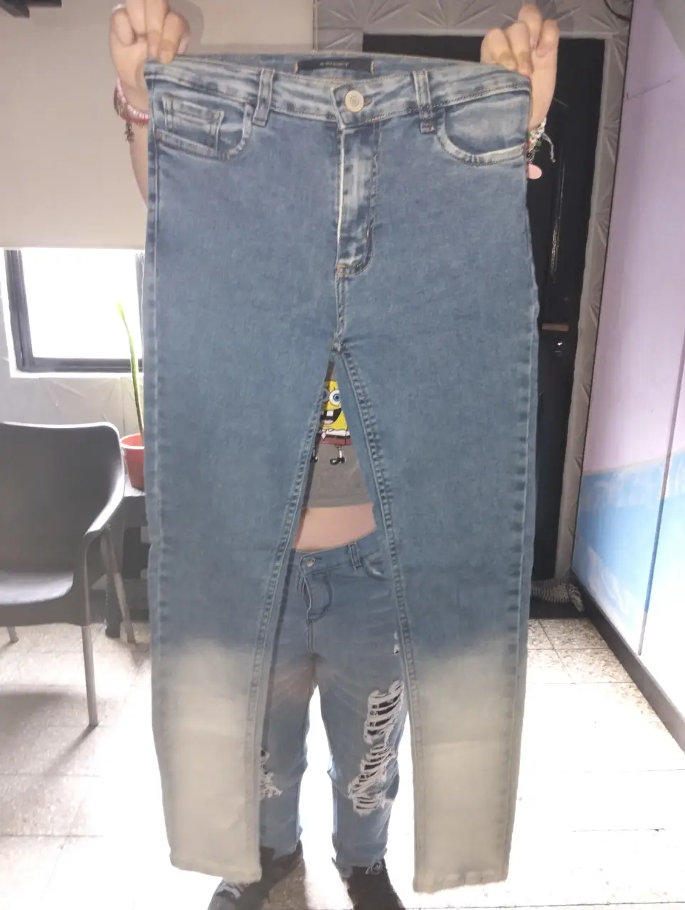 Jeans de mujer tiro alto con roturas en las rodillas y efecto gastado en la parte inferior de las piernas. Ideal para un look casual y moderno.