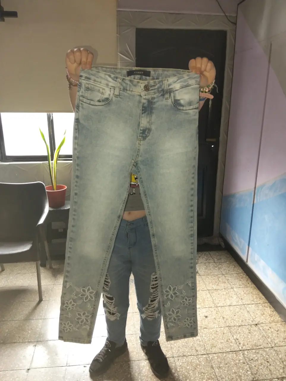 Jeans celeste com detalles florales en los bajos. Tiro medio, ideal para un look casual y moderno.