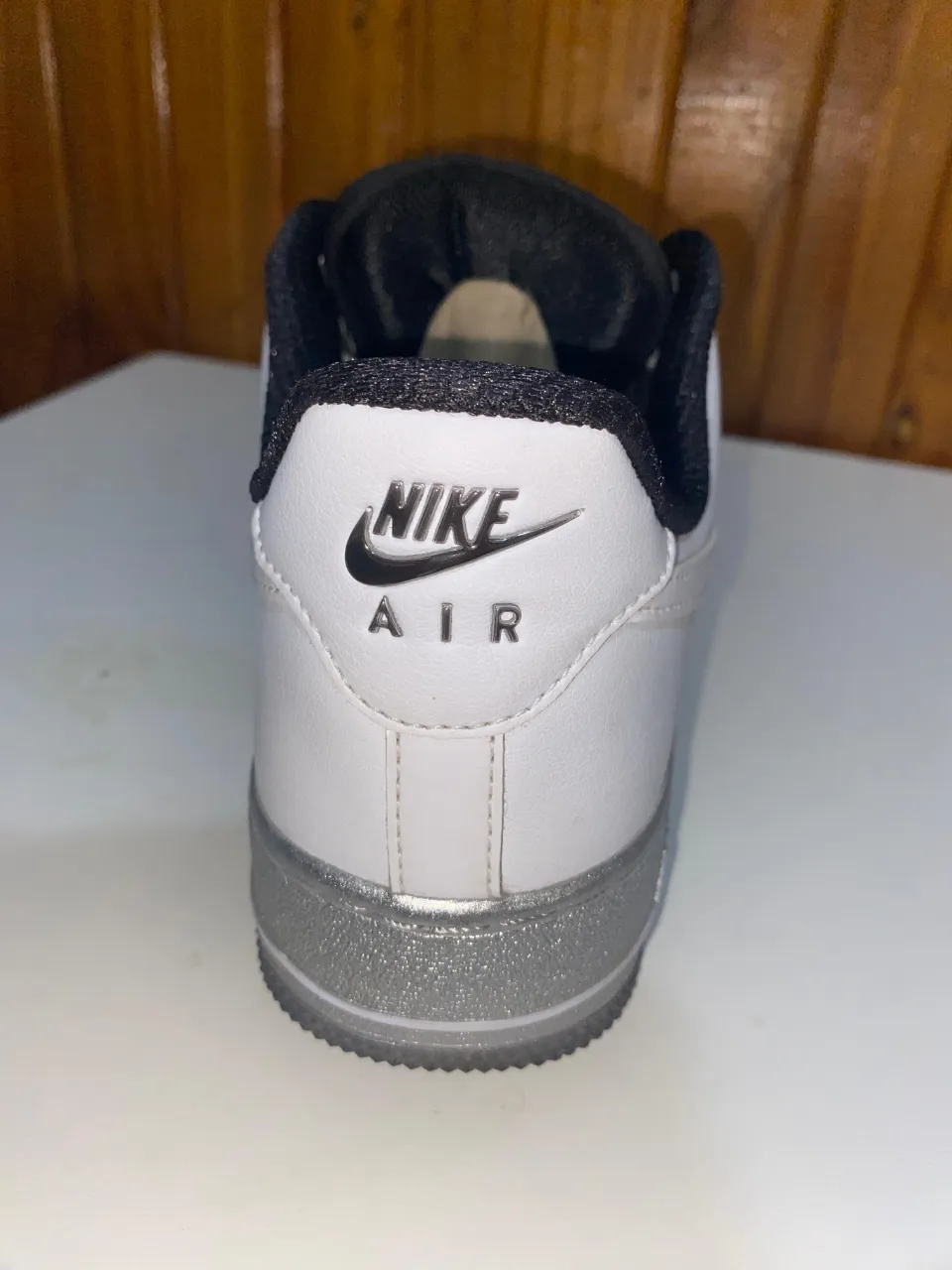 Zapatillas Nike Air Force 1 blancas con detalles en gris plateado. Diseño clásico y atemporal, ideales para un look casual y urbano.