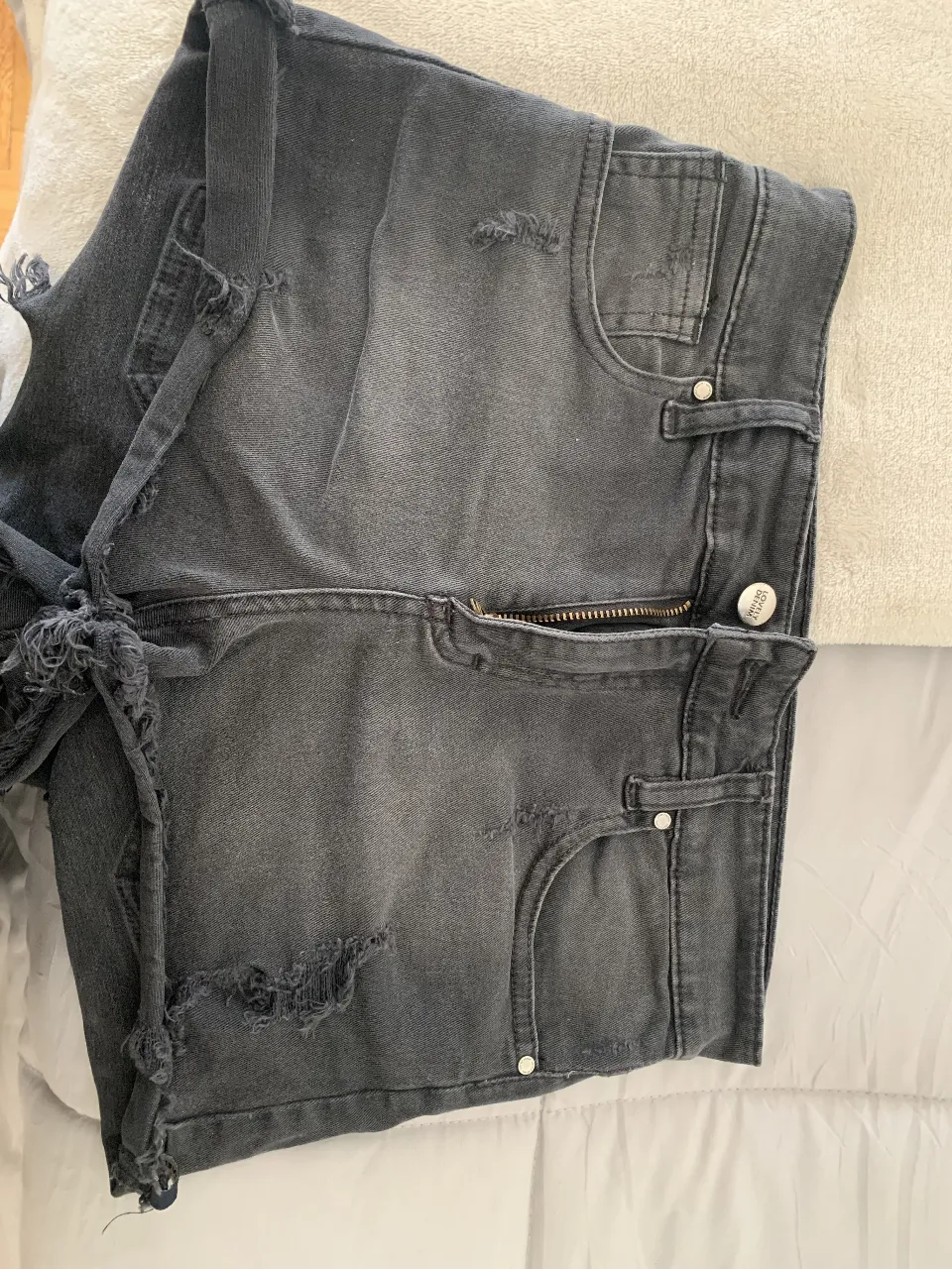 Short de jean negro con detalles rotos y desflecado. Talle 24, tiro alto. Ideal para un look casual y moderno.