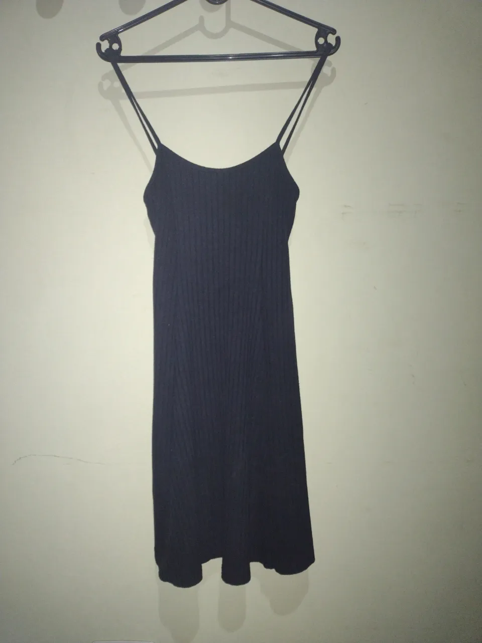 Vestido negro de tiras finas, con escote recto y espalda baja. La tela es acanalada.