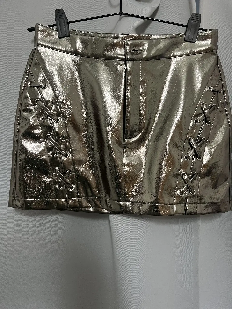 Minifalda plateada con detalles de cordones en los laterales. Ideal para un look de fiesta o salida.