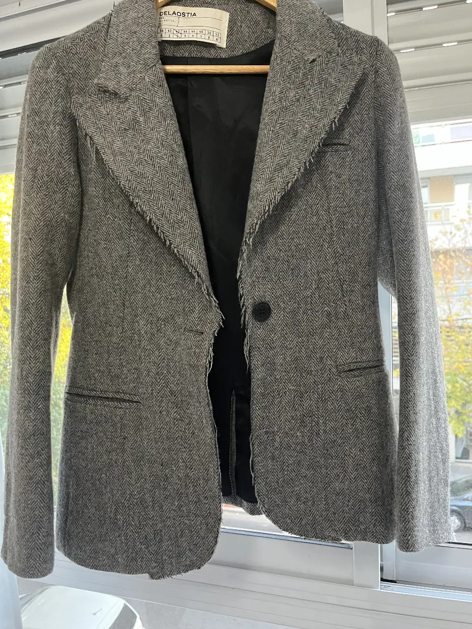 Blazer de mujer gris con diseño de espiga. Corte entallado, con un solo botón y solapas con detalle desflecado. Ideal para un look elegante y sofisticado.