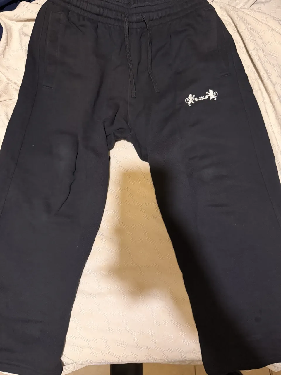 Pantalón de algodón negro con cordón en la cintura y logo bordado en la pierna izquierda. Etiqueta interior de la marca Nike.